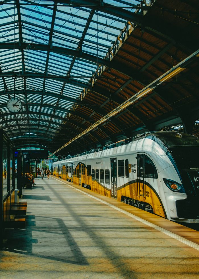 portfolio-02 A modern train station featuring a sleek train under a glass ceiling, showcasing urban travel.